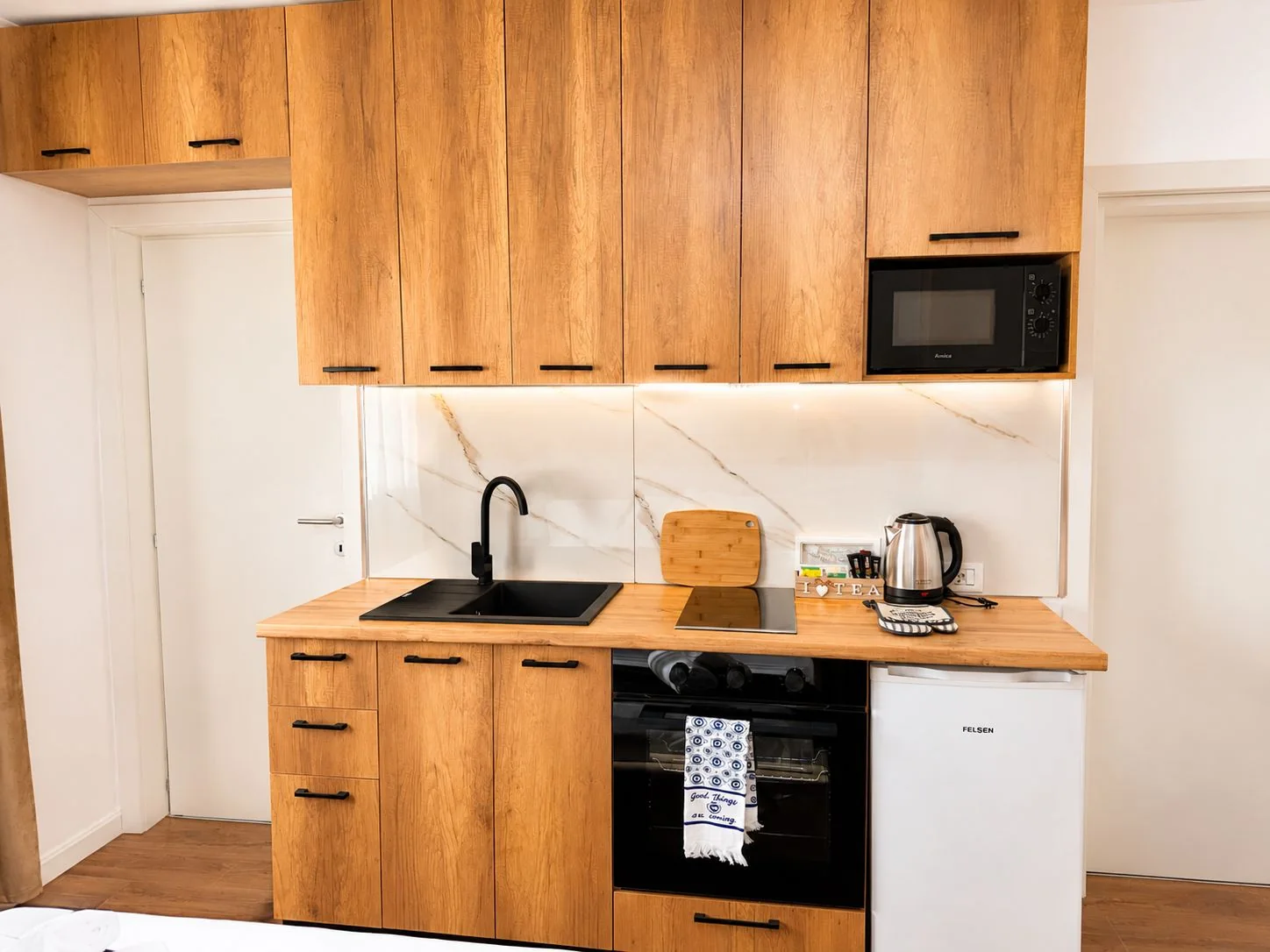 Fully equipped kitchen with oak cabinets, oven, electric hob, microwave, kettle, sink and fridge