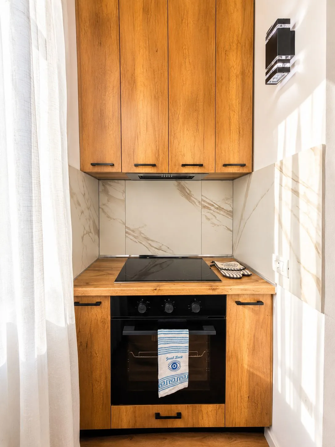 Kitchen corner with oven, electric hob, extractor hood and marble-effect splashback