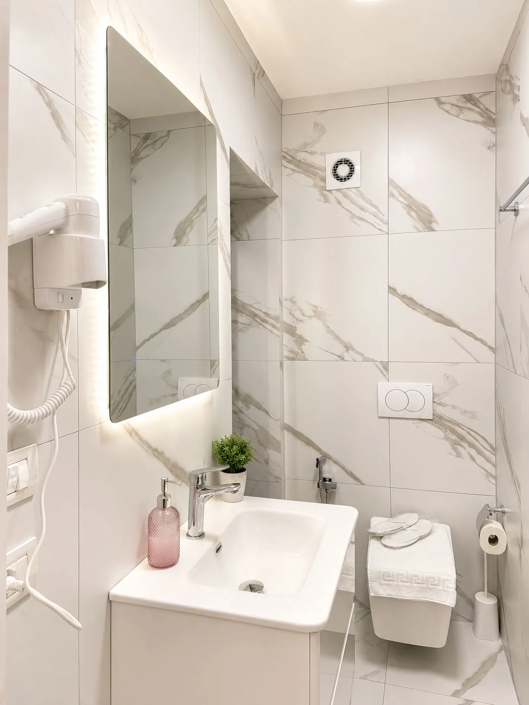 Private bathroom with marble-effect tiles, backlit mirror, washbasin, hair dryer and fresh towels